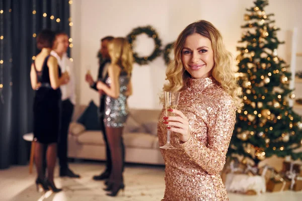 彼女の友人の前に立っている女性 人々のグループは屋内で一緒に新年のパーティーを持っています — ストック写真