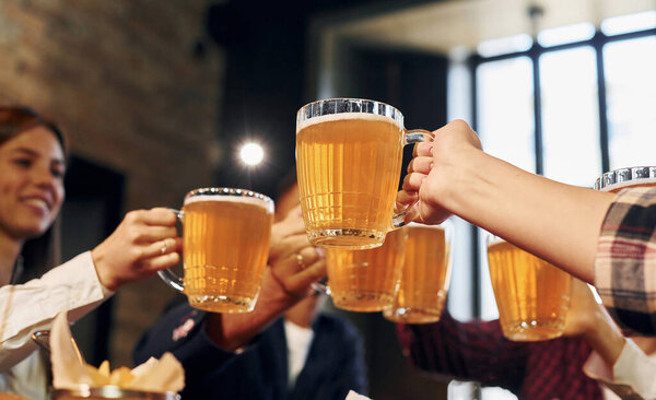 Аплодируем вместе. Группа молодых друзей, сидящих в баре с пивом.