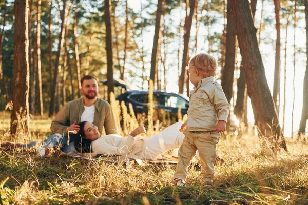 女の子は散歩している 父と母と娘の幸せな家族が森の中にいる — ストック写真