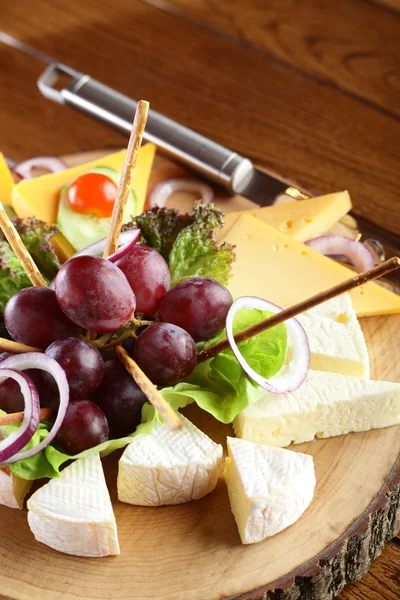 Dřevěná miska se sýrem a ovocem — Stock fotografie