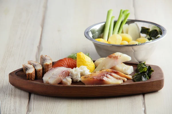 Assortiment de poissons salés avec pomme de terre sur assiette en bois — Photo