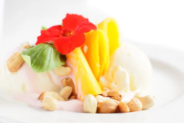 Mango ice cream with nuts and flowers — Stock Photo, Image