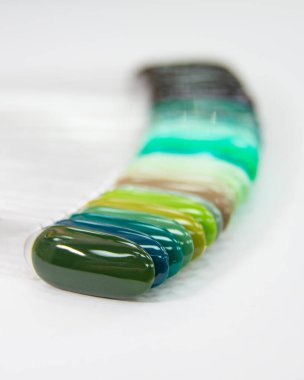 Çok renkli farklı palet jeli beyaz arkaplanda manikür örneklerini parlatır