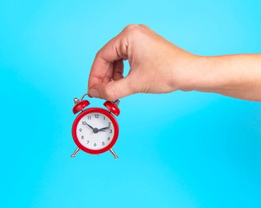 Çalar saat kırmızı kadın eli parlak mavi arkaplan