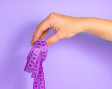 Violet 'in parlak arka planında kadın eli üzerinde mor şerit ölçü diyeti kavramı