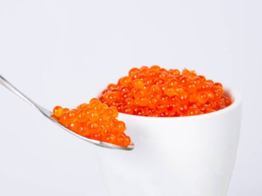 Beyaz arka planda izole edilmiş gümüş kaşıkta kırmızı havyar.