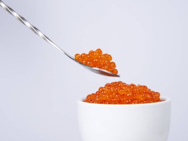 Beyaz arka planda izole edilmiş gümüş kaşıkta kırmızı havyar.