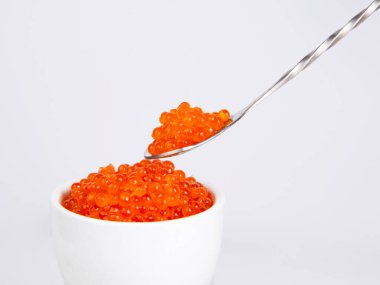 Beyaz arka planda izole edilmiş gümüş kaşıkta kırmızı havyar.