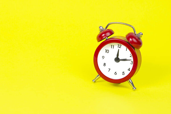 Red alarm clock on yellow paper isolated background with space for text