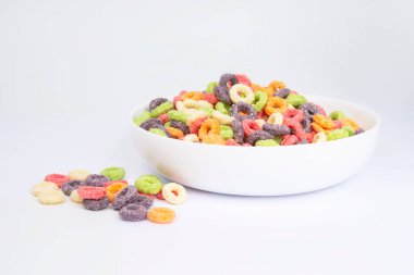 Lezzetli ve besleyici meyveli gevrek döngüleri beyaz arka planda çok renkli, sağlıklı ve komik çocukların kahvaltısına ilave olarak.