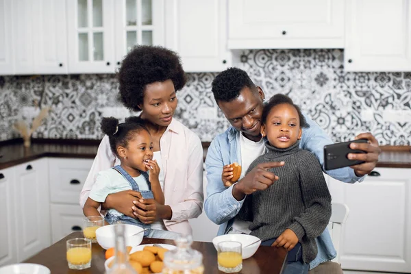 Família africana usando celular durante o café da manhã na cozinha — Fotografia de Stock