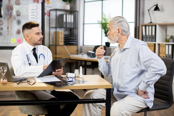 Male doctor with clipboard listening to senior patient