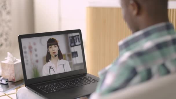 코트와 헤드셋을 착용하고 비디오 전화를 통해 원격으로 환자와 상담하는 유럽 여성 gp doctor — 비디오