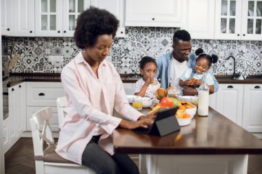 Anne çalışırken iki çocuk mutfakta babalarıyla oynuyorlar.