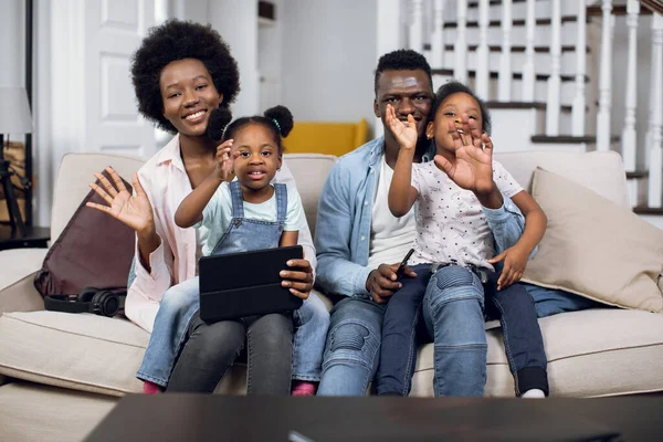Positive african family using tablet while resting on couch