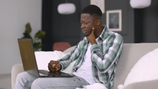 Άρρωστος Αφρικανός με καθημερινά ρούχα, με θερμόμετρο στα χέρια, βιντεοκλήση με γιατρό στο laptop — Αρχείο Βίντεο
