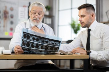 Yaşlanmış herapist iş adamına röntgen raporunu açıklıyor