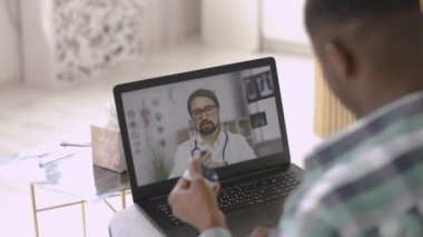 Nabız oksimetresi olan bir adam dizüstü bilgisayardaki erkek doktorun eğitim videosunu izliyor.