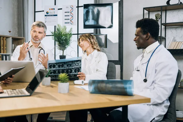 Çok kültürlü doktorlar hasta tedavisi hakkında toplantı yapıyorlar.