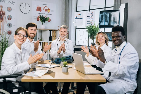 Médecins multiraciaux applaudissant et souriant au bureau — Photo