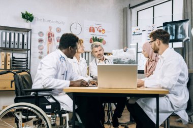 Bilgisayarda video konferansı yapan çeşitli tıp çalışanları, hastanın röntgen taramasını tartışıyorlar.