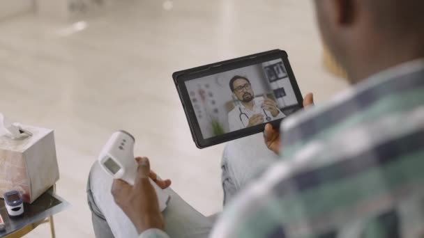 Zurück verschwommenen Blick des afrikanischen Mannes, beobachten Videoblog des Arztes, erklärt, wie man Thermometer verwenden — Stockvideo