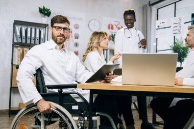 Tekerlekli sandalyedeki doktor çeşitli meslektaşlarla işbirliği yapıyor.