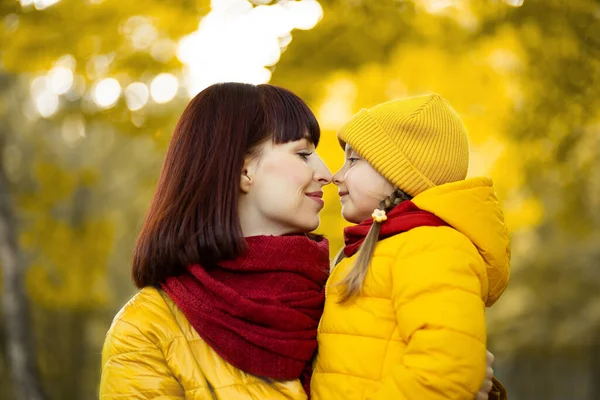 Jovem mãe afetuosa abraçando sua linda menina criança e olhando uns para os outros, passando o dia de outono juntos em belo parque amarelo ou floresta. — Fotografia de Stock