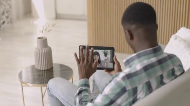 Afrikalı bir adam evde en iyi kız arkadaşıyla görüntülü konuşma yapmak için tablet bilgisayar kullanıyor..