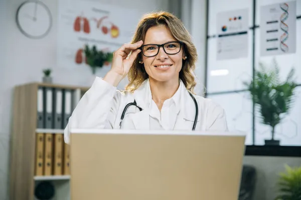Női orvos szemüvegben dolgozik laptop a szekrényben — Stock Fotó