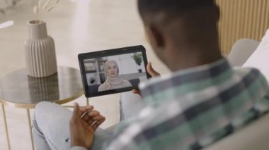 Müslüman kadın tesettürlü tablet bilgisayar ekranı, Afrikalı erkek arkadaşıyla çevrimiçi görüntülü sohbet yoluyla konuşuyor