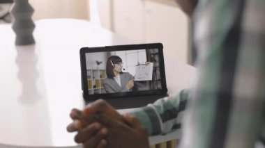 Tablet bilgisayarlı Afrikalı Amerikalı bir adam bayan meslektaşıyla görüntülü görüşme yapıyor.