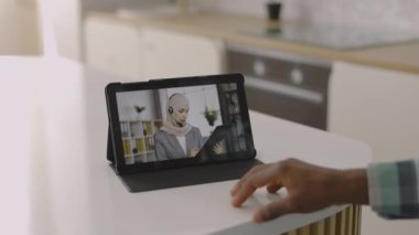 Erkek, kadın Müslüman CEO ya da finans uzmanıyla tabletteki video konferans uygulamasını kullanarak konuşuyor.