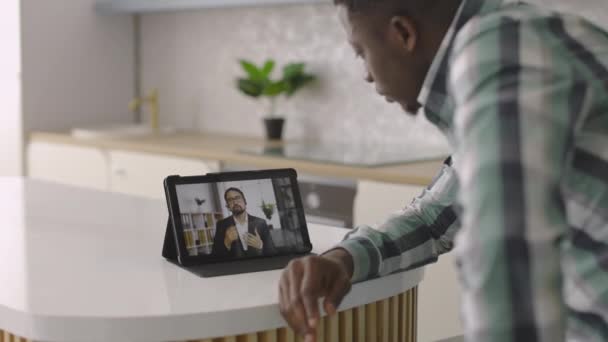 Hombre africano usando tableta para videollamada con su pareja, dando recomendaciones — Vídeo de stock
