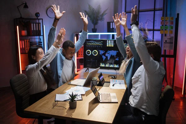 Heureux financiers multiraciaux assis au bureau les mains en l'air — Photo