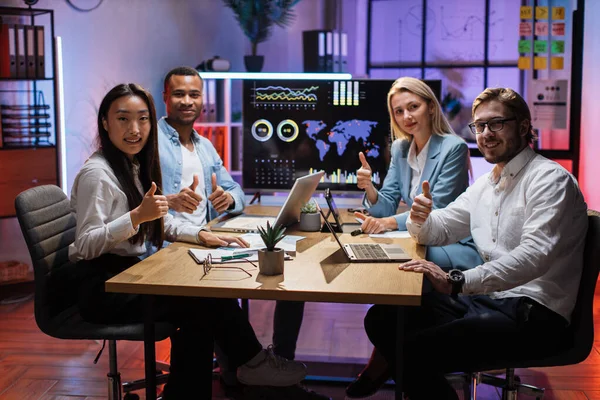 Fyra multietniska kontorsarbetare visar tummen upp på kameran — Stockfoto