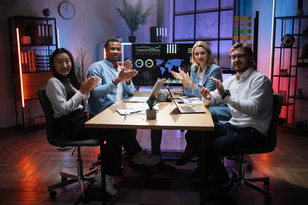 Multiracial team av proffs applåderar medan du sitter vid skrivbordet — Stockfoto