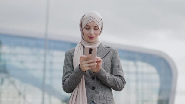 Empresária árabe de pé em frente ao edifício moderno com celular — Vídeo de Stock