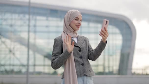 Muselman kvinna hälsning hennes vän med viftande hand, har video samtal utanför — Stockvideo