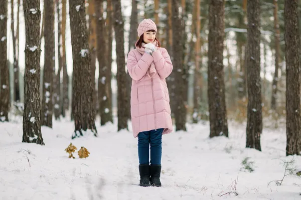 Mulher de 30 anos bonita em casaco rosa elegante, boné e cachecol, desfrutando de caminhada na bela floresta de inverno nevado. Retrato sazonal de inverno ao ar livre de senhora caucasiana feliz. — Fotografia de Stock