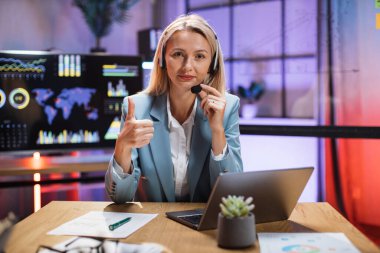 Kulaklık takan iş kadını modern laptopta görüntülü konuşma yapıyor.