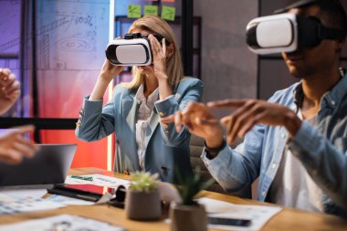 VR gözlüklü iş arkadaşları ofiste oturuyorlar.