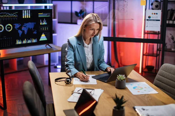 Retrato de mujer en traje escribiendo notas y usando laptop —  Fotos de Stock