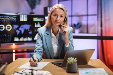 Kulaklık takan iş kadını modern laptopta görüntülü konuşma yapıyor.