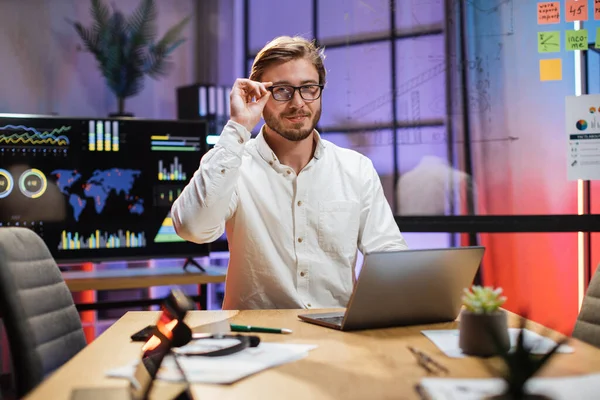 Pria berkacamata duduk di kantor dan menggunakan laptop nirkabel — Stok Foto