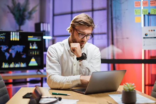 Homem focado digitando no laptop enquanto sentado no escritório — Fotografia de Stock