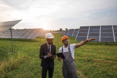 Güneş santralinin ortasında duran teknisyen ve müfettiş