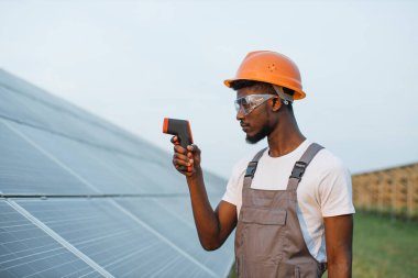 Güneş çiftliğinde termal görüntüleyici kullanan kasklı teknisyen.