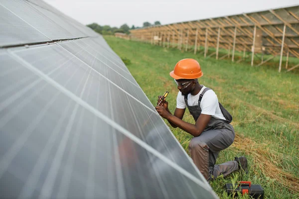 Üniformalı adam güneş panellerini tamir etmek için tornavida kullanıyor.