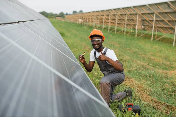 Miğferli ve gözlüklü adam güneş panellerinde fındıkları sıkıyor.